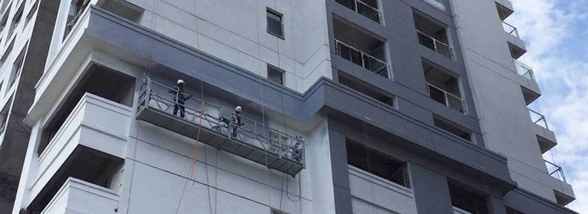 The exterior wall of the DI RIVIERA high-rise building in Cambodia is painted with like stone paint. Workers are hanging and spraying ADD STONE like stone paint.