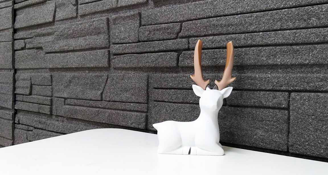 黒いストーンテクスチャウォールパネルと白い鹿の彫刻