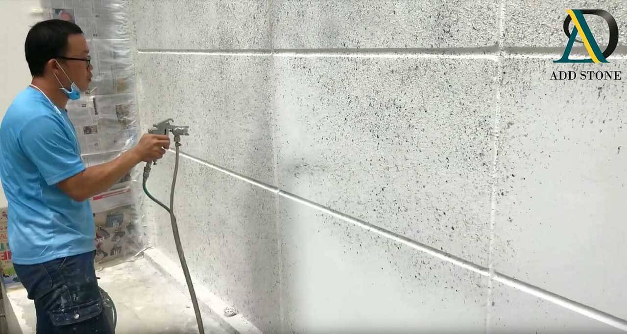 The technician is spraying main coating of ADD STONE Faux-Stone Coating System with a spray gun. 